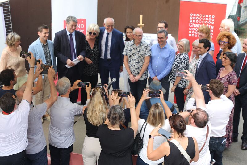 des personnes posent devant un panneau avec des signatures pendant que des personnes prennent des photos